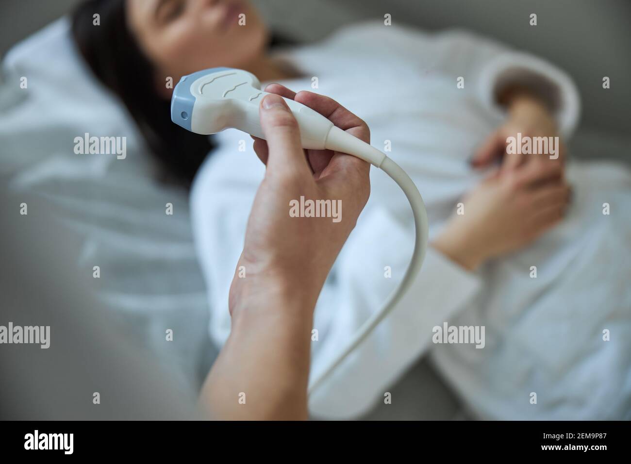 Medico che esegue un esame a ultrasuoni con un trasduttore a ultrasuoni Foto Stock