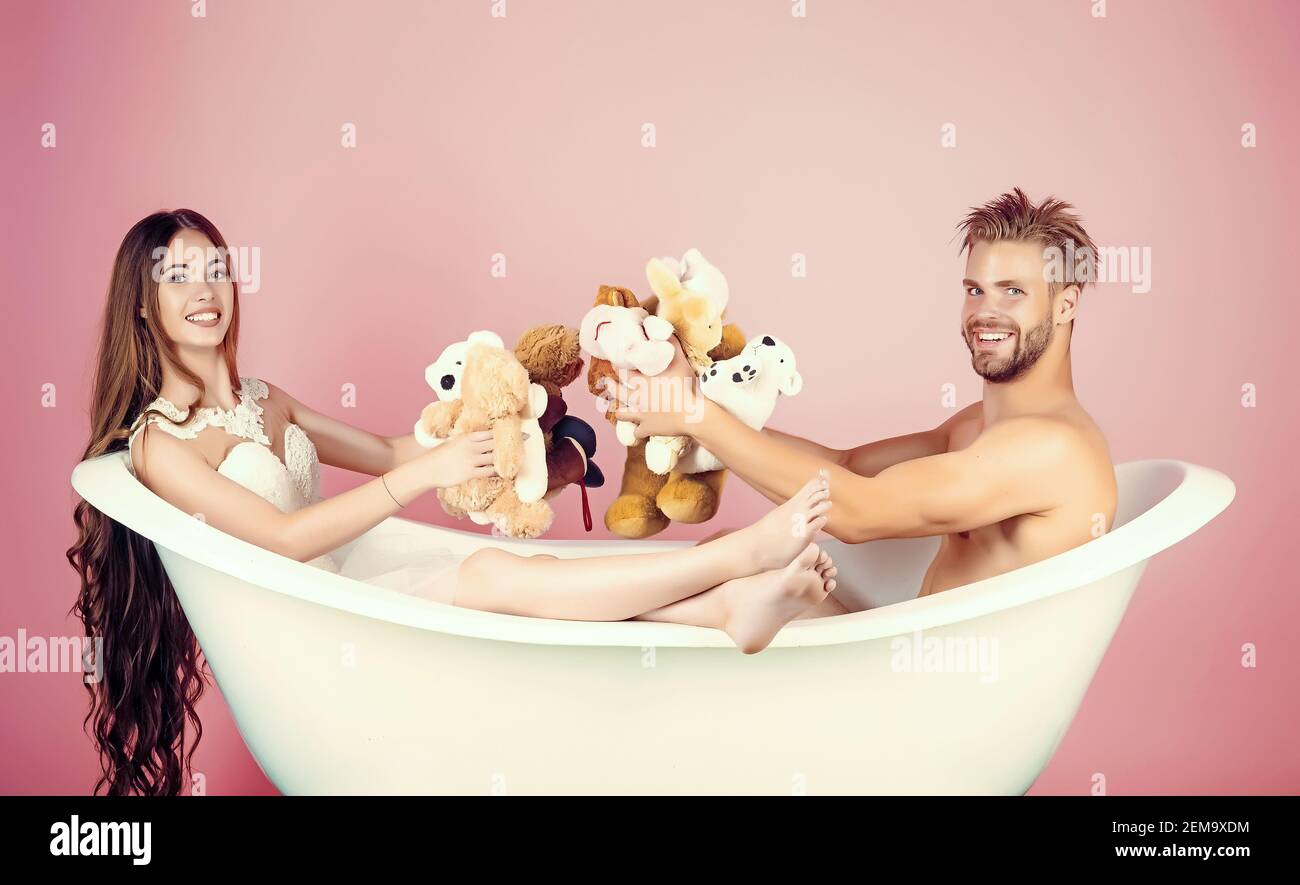 Coppia in bagno. Fidanzato e fidanzata si rilassano nella vasca da bagno su  sfondo rosa. Uomo in vasca da bagno vicino alla ragazza con capelli lunghi.  Amore e romanticismo Foto stock -