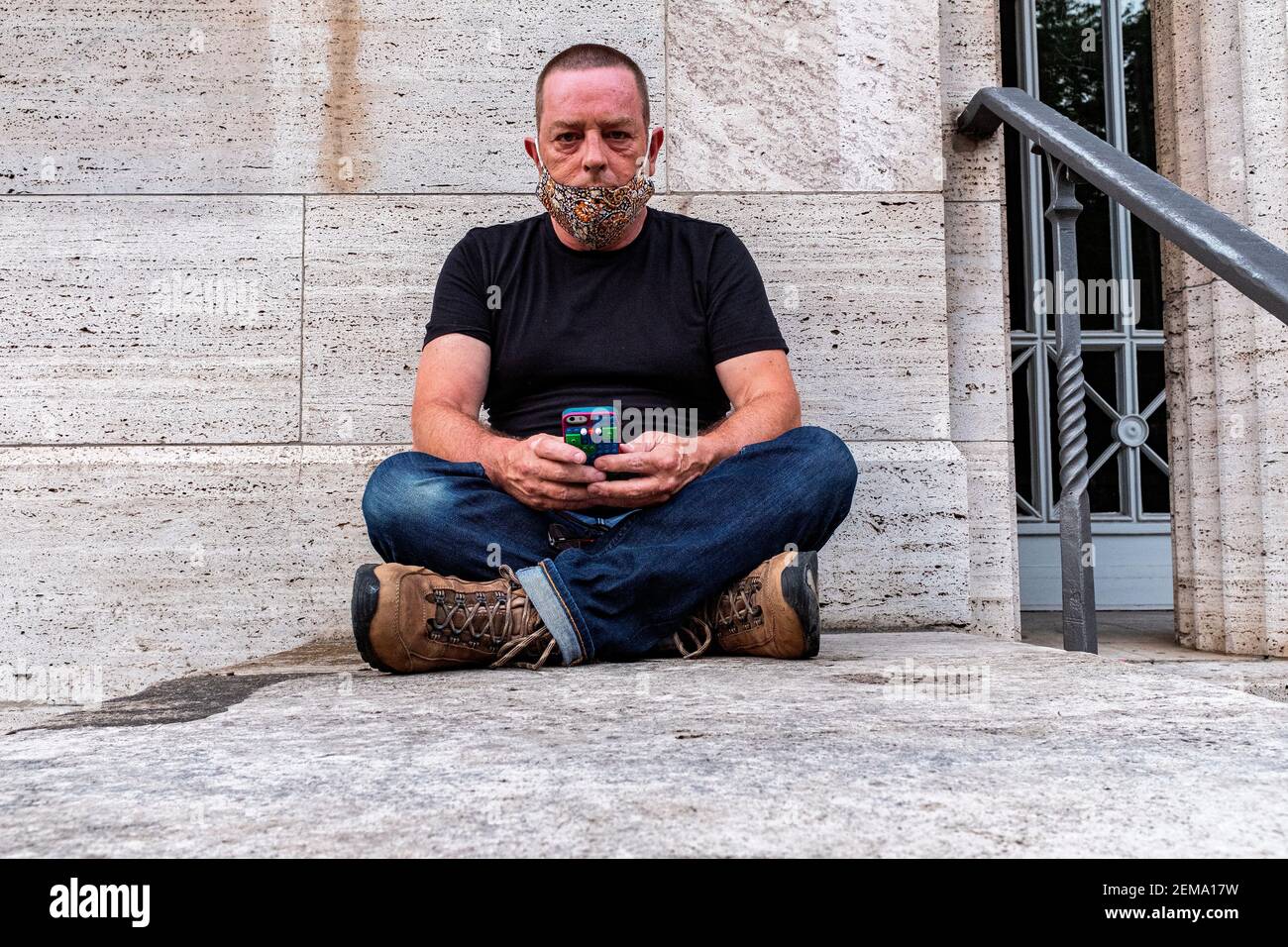 Berlino, Germania, Ritratto di un adulto maturo, maschio caucasico seduto contro una parete grigia. Foto Stock