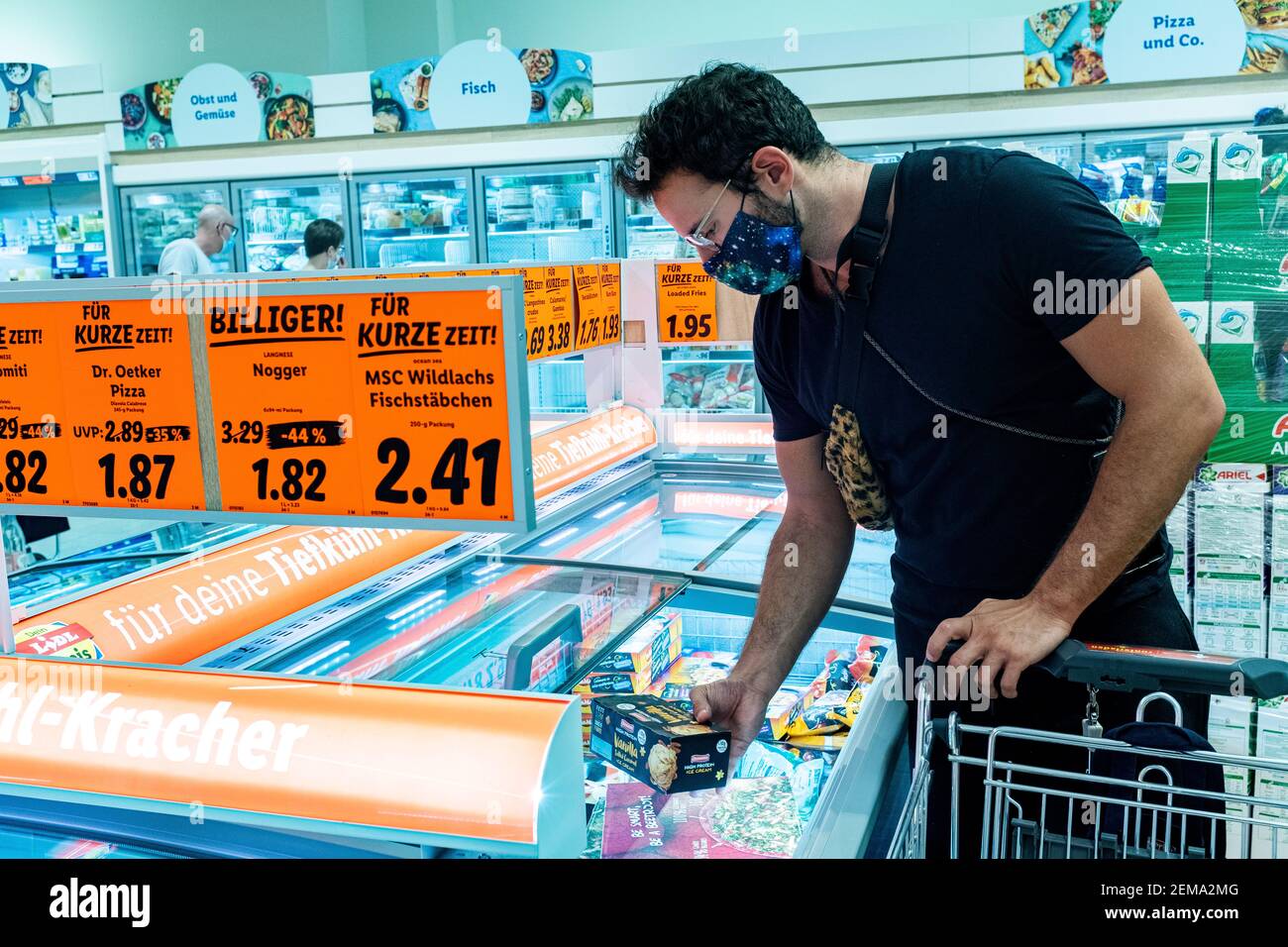 Berlino, Germania. Mature gay maschio shopping per generi alimentari all'interno di un supermercato locale che indossa un facemask '[rotective' a causa dell'epidemia di Corona. In Germania Foto Stock