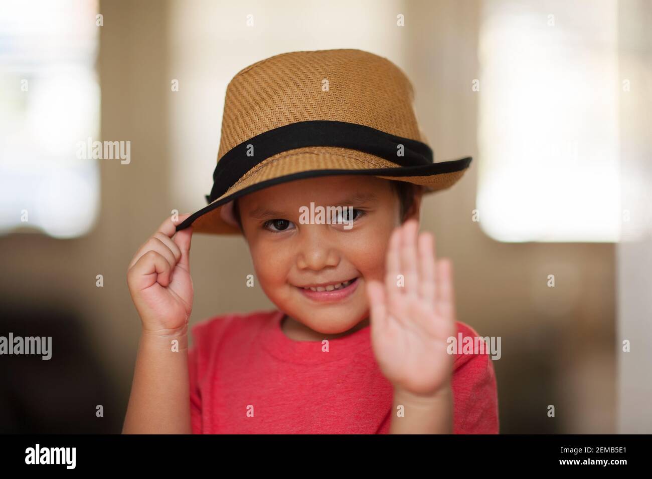 Un ragazzo carino che esegue la punta del cappello con un sorriso sul viso, per esprimere gratitudine o un saluto convenzionale. Foto Stock