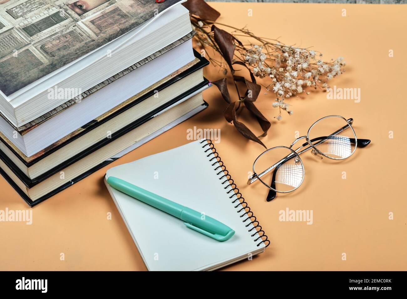 Libri, taccuino, penna e occhiali su sfondo arancione Foto Stock