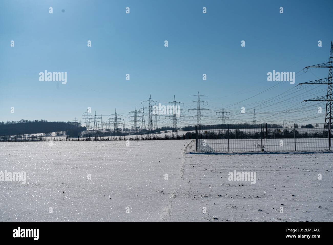 Palo elettrico realizzato in materiale naturale in un paesaggio invernale con un cielo blu chiaro Foto Stock