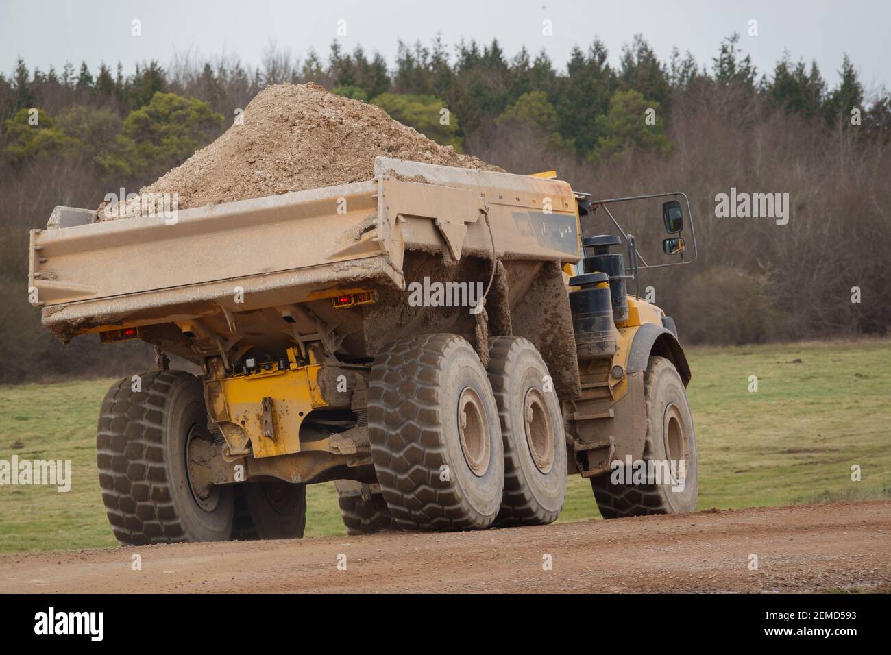 Gialle Volvo A40E dumper a terra articolato completamente carico con 25 tonnellate di carico che guida attraverso Salisbury Plain, Wiltshire UK Foto Stock