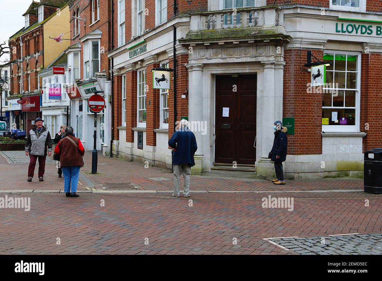 Ashford, Kent, Regno Unito. 25 febbraio 2021. I casi settimanali del coronavirus sono diminuiti considerevolmente ad Ashford con 71.5 casi per 100,000 popolazione. Persone che aspettano fuori Lloyds banca nel centro città alta strada. Photo Credit: Paul Lawrenson/Alamy Live News Foto Stock