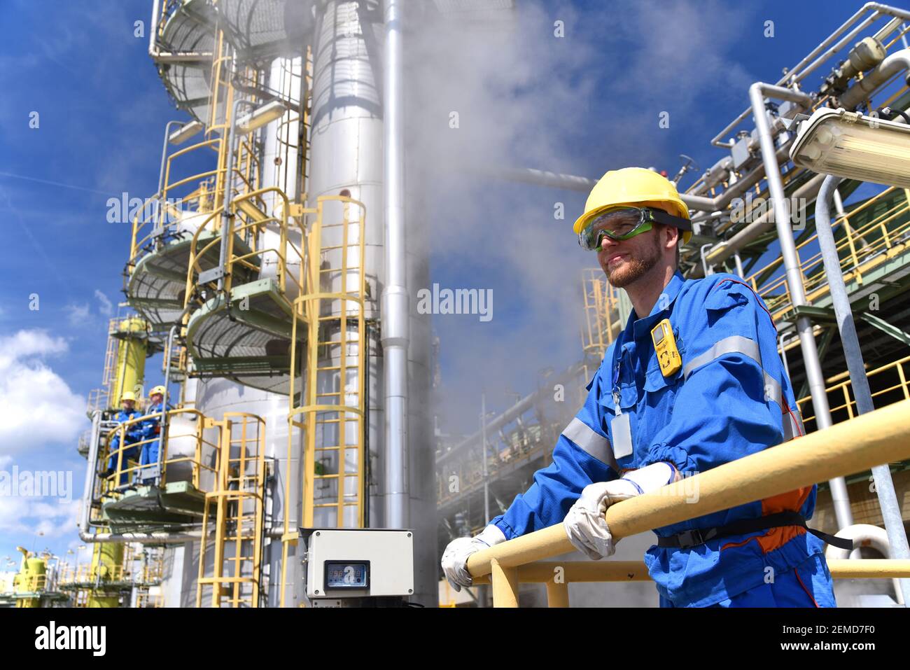 impianto chimico - lavoratori in abiti da lavoro in raffineria con tubi e macchinari Foto Stock