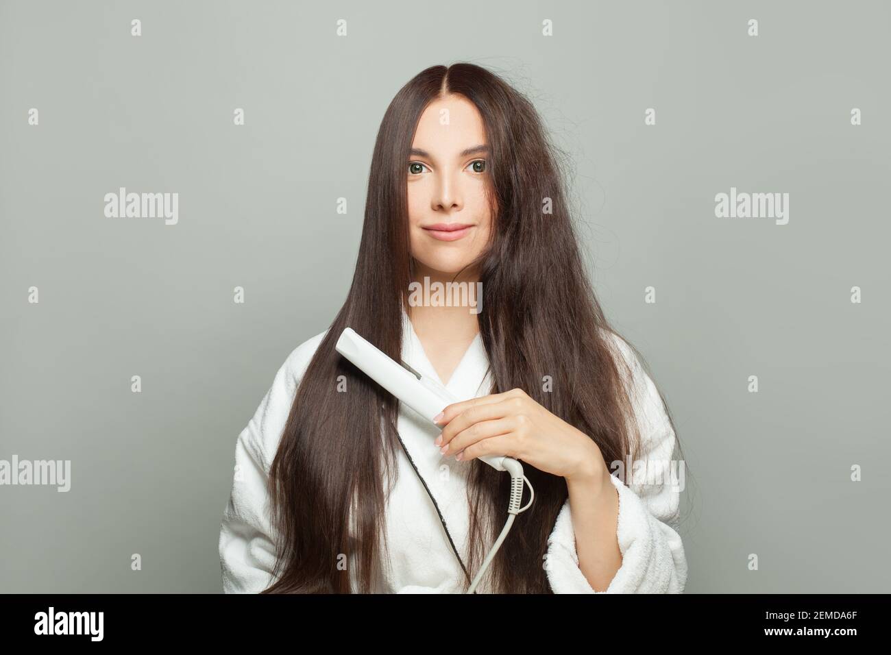 Bella donna raddrizzare i capelli su sfondo bianco. Concetto di cura dei capelli Foto Stock