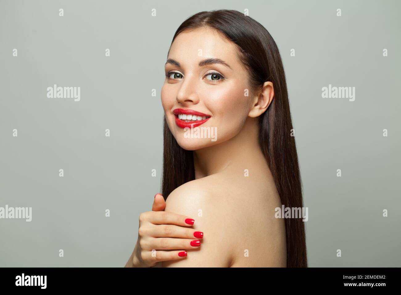 Modello donna di moda bruna felice con pelle chiara e lunga capelli sani e dritti sorridenti su sfondo bianco Foto Stock