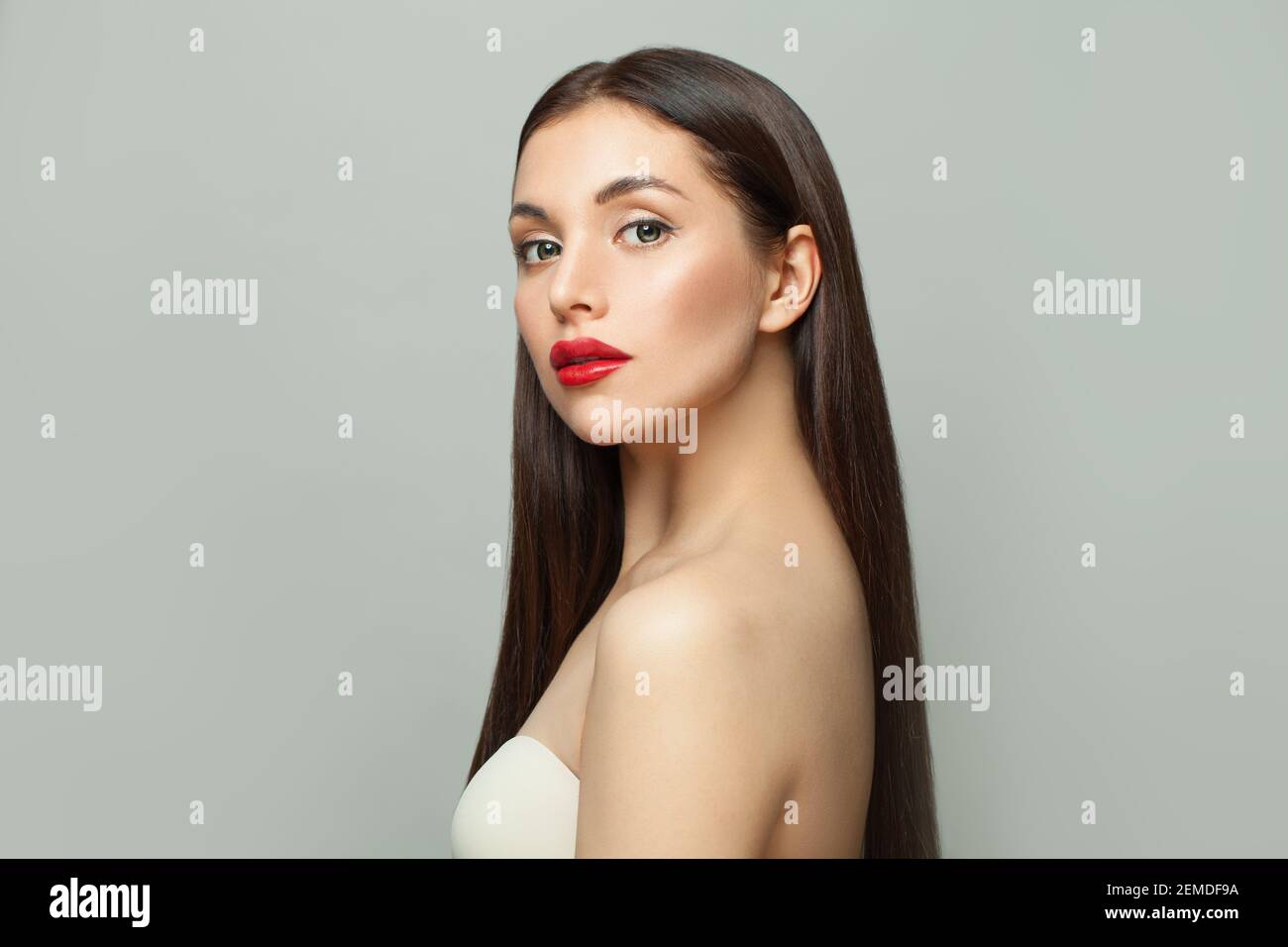 Celebrità moda modello donna brunette con pelle chiara e lungo capelli lisci sani su sfondo bianco Foto Stock