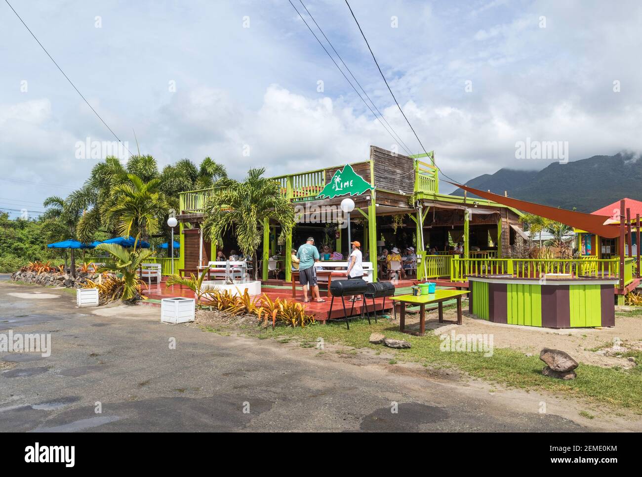 Il Lime Bar multicolore a Pinney's Beach sui Caraibi isola di Nevis al sole piena di persone che mangiano e. bere in modo rilassato Foto Stock