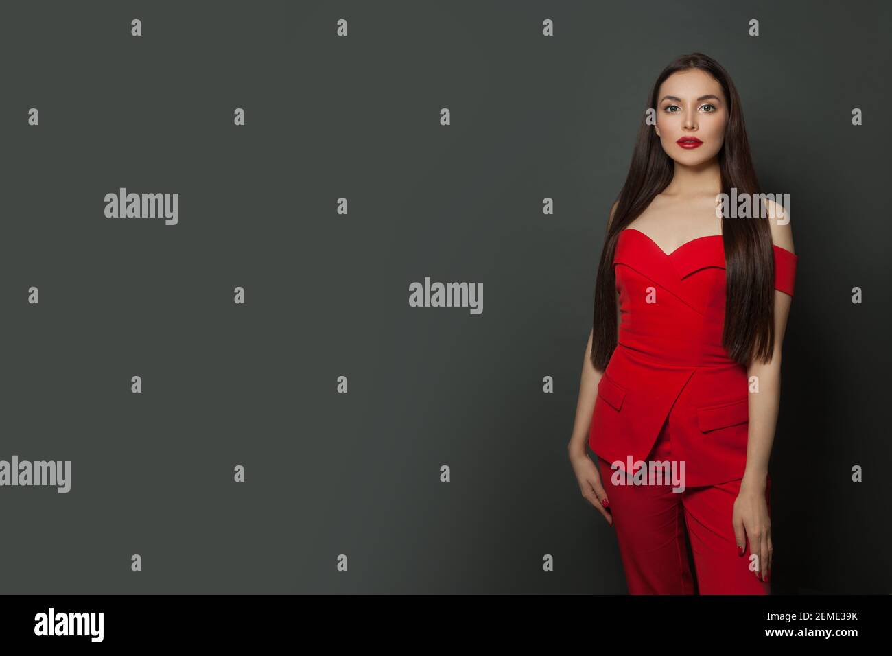 Elegante modello donna di moda con jumpsuit rosso su striscione nero sfondo Foto Stock
