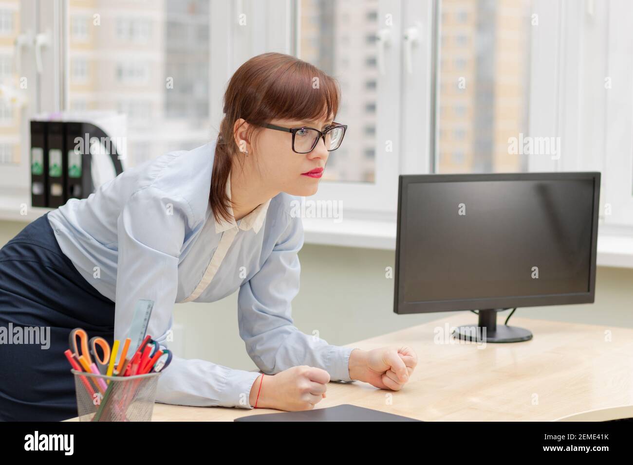 giovane capo donna stretto in occhiali e una blusa blu in ufficio al