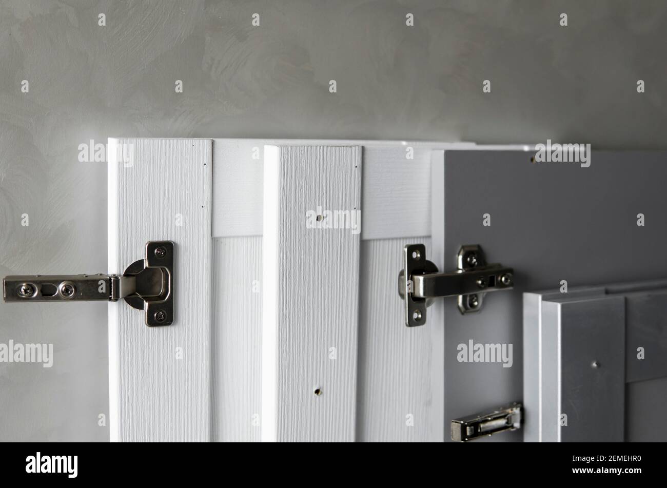 Anello per mobili per truciolare, installato su una cucina bianca e grigia frontale in materiale mdf. Accessori per carpenteria utilizzati nella costruzione di Foto Stock