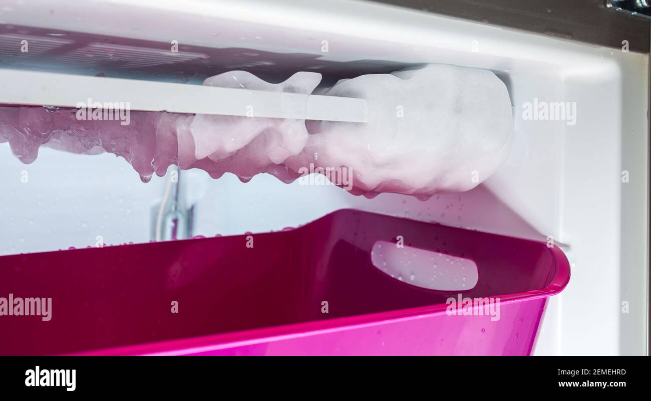 Processo di scongelamento del ghiaccio in un congelatore domestico. Raccolta di acqua in un bacino di plastica. Foto Stock