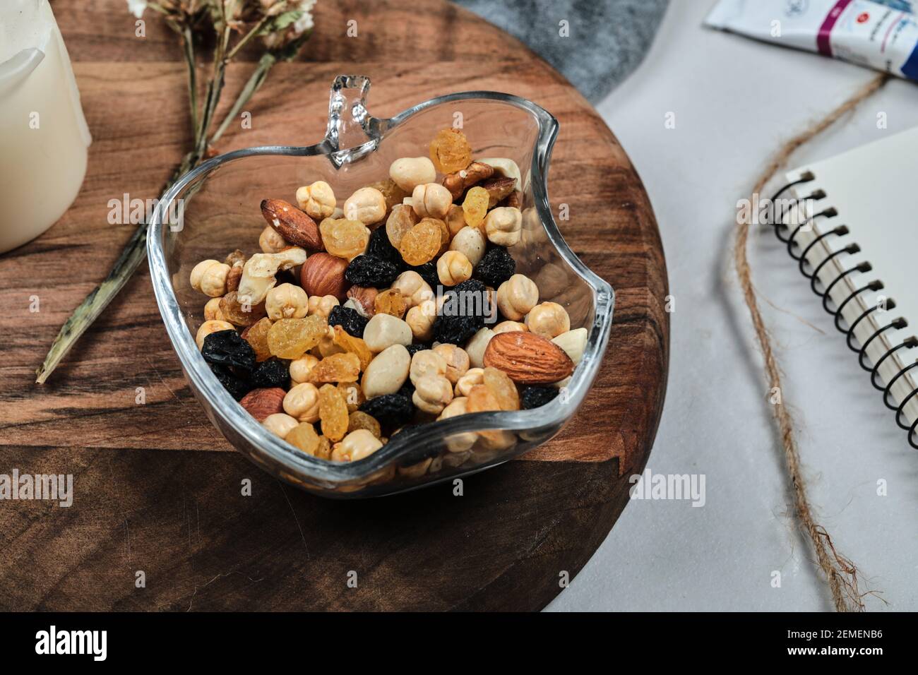 Un piatto di noci con candela, fiore, carta e tubi sulla tavola di legno Foto Stock