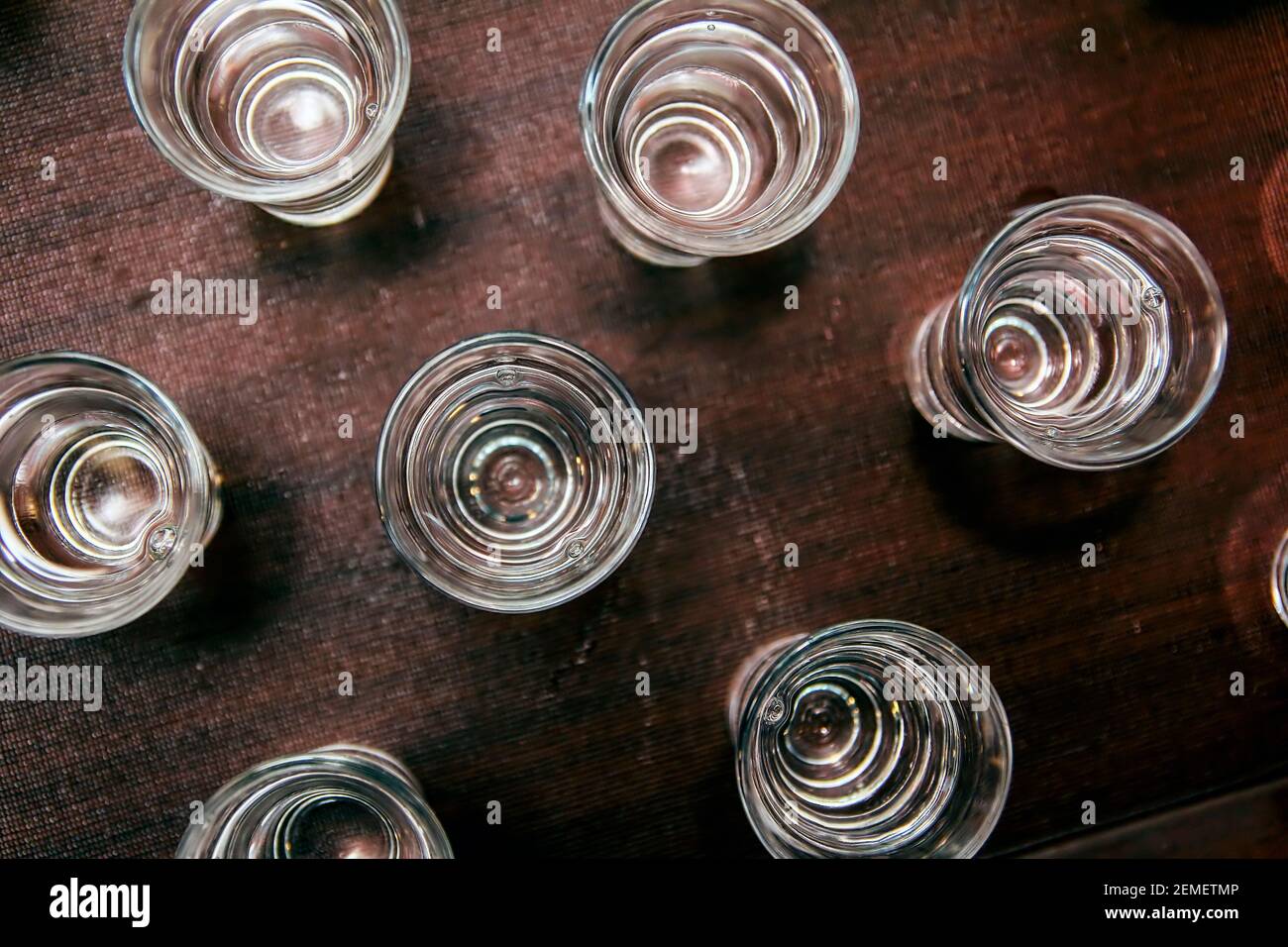 Bicchieri da shot con palinka, brandy, vodka o qualsiasi liquido trasparente su tavolo marrone. Immagine per partito o alcolismo; foto a colori. Foto Stock