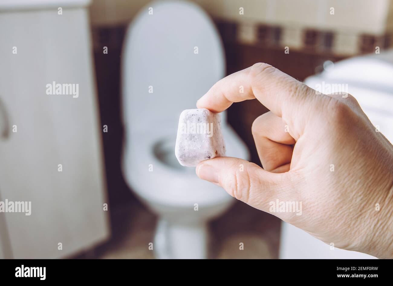 Bomba fizzie da toilette fai-da-te per la pulizia della ciotola della toilette domestica. Fuoco selettivo sulla mano della donna, tenendo la pastiglia di pulizia naturale fatta in casa. Ecocompatibile. Foto Stock