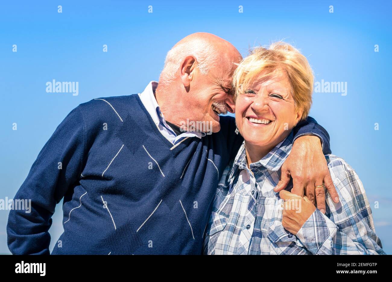 Felice coppia anziana innamorata durante il pensionamento - gioiosa anziana stile di vita con l'uomo che sussurra e sorride con sua moglie Foto Stock