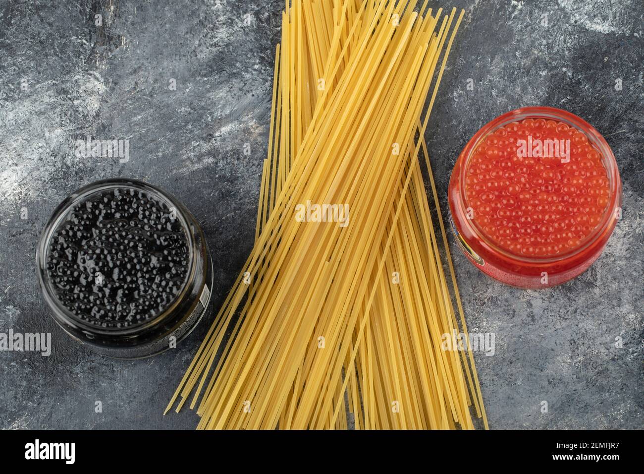 Lastre di vetro piene di caviale rosso e nero su a. sfondo in marmo Foto Stock