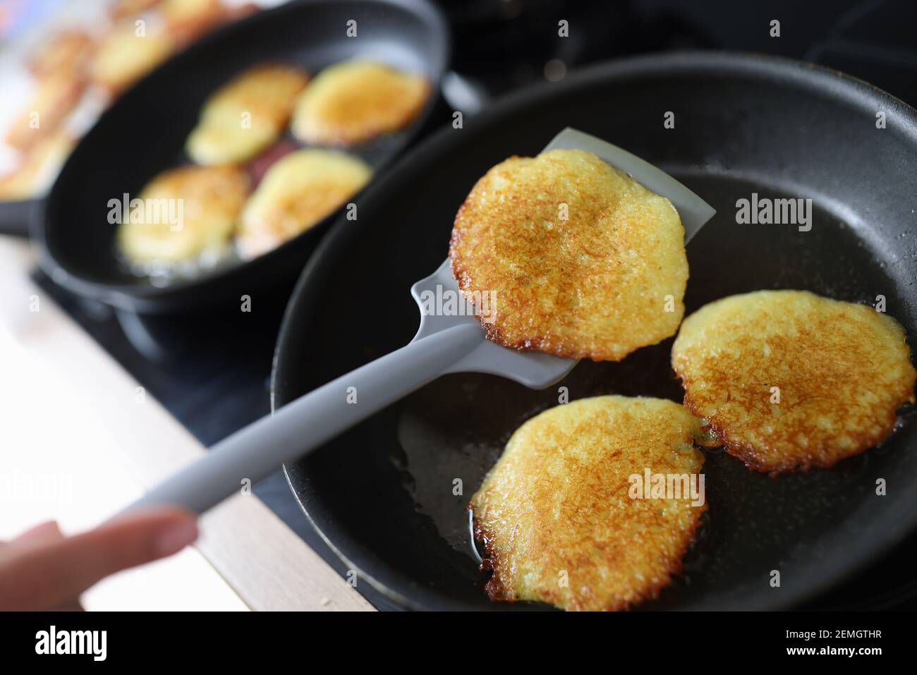 Chef che trasforma le frittelle di patate con la spatola closeup Foto Stock