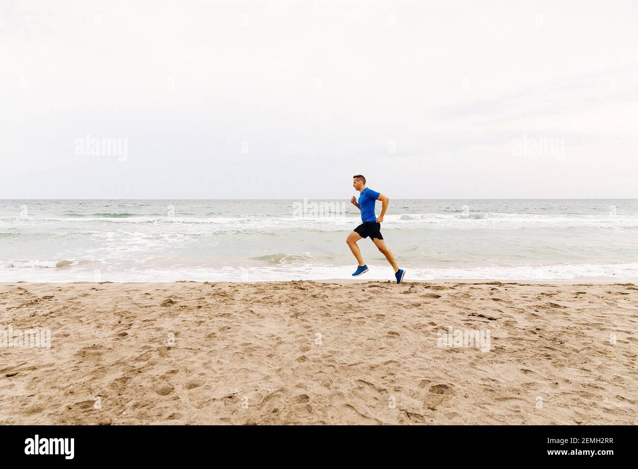 uomini jogger correre spiaggia sabbiosa sullo sfondo del mare e. cielo Foto Stock