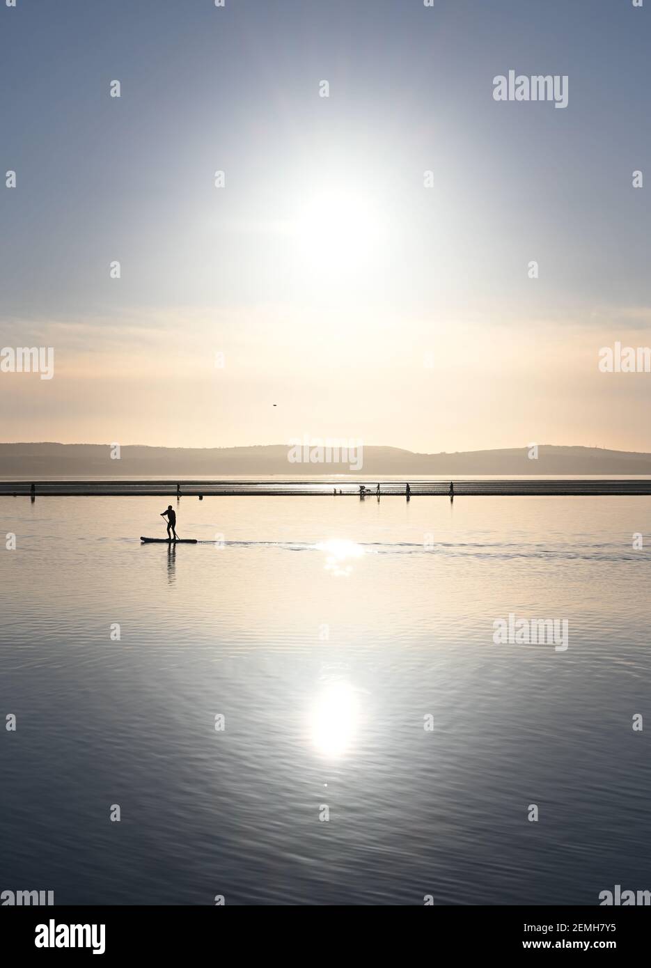 Un paddle boarder pagaia lungo West Kirby Marine Lake ON Il Wirral nel febbraio 2021 Foto Stock