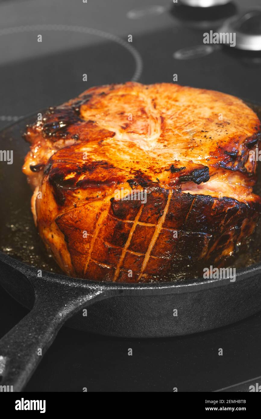 Ricerca di una giuntura glassata di prosciutto di gammon di carne. In una padella in ghisa su un piano cottura. Foto Stock