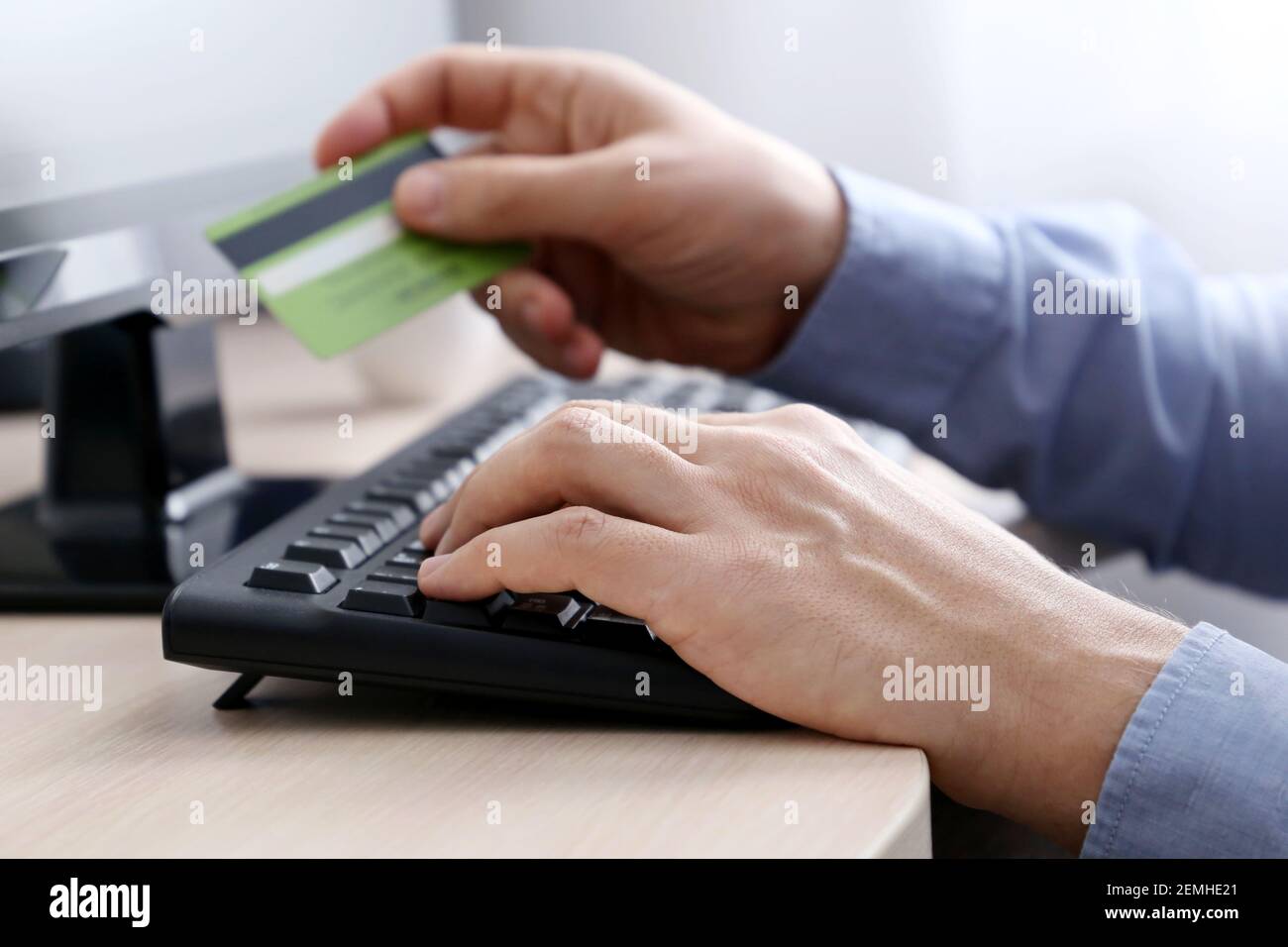Uomo che detiene carte di credito sulla tastiera del PC. Concetto di acquisto e pagamento online, transazioni finanziarie Foto Stock