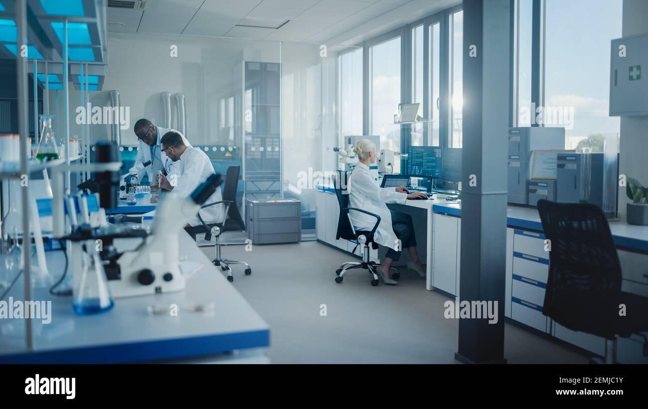 Modern Medical Research Laboratory: Team di scienziati che lavorano con le pipette, analizzando i campioni biochimici, parlando. Laboratorio scientifico per la medicina Foto Stock