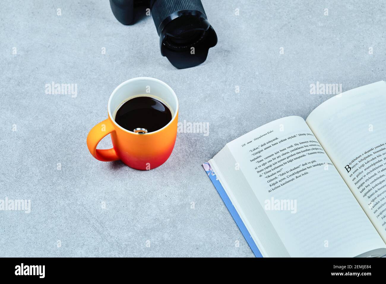 Apri libro, fotocamera e tazza di caffè sul tavolo grigio Foto Stock