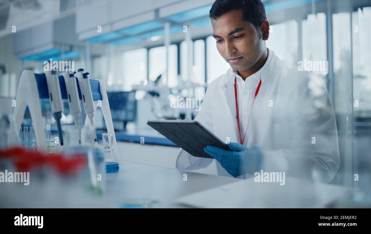 Medical Research Laboratory: Ritratto di un bel scienziato maschile che utilizza il computer Digital Tablet per analizzare i dati. Advanced Scientific Lab for Medicine Foto Stock