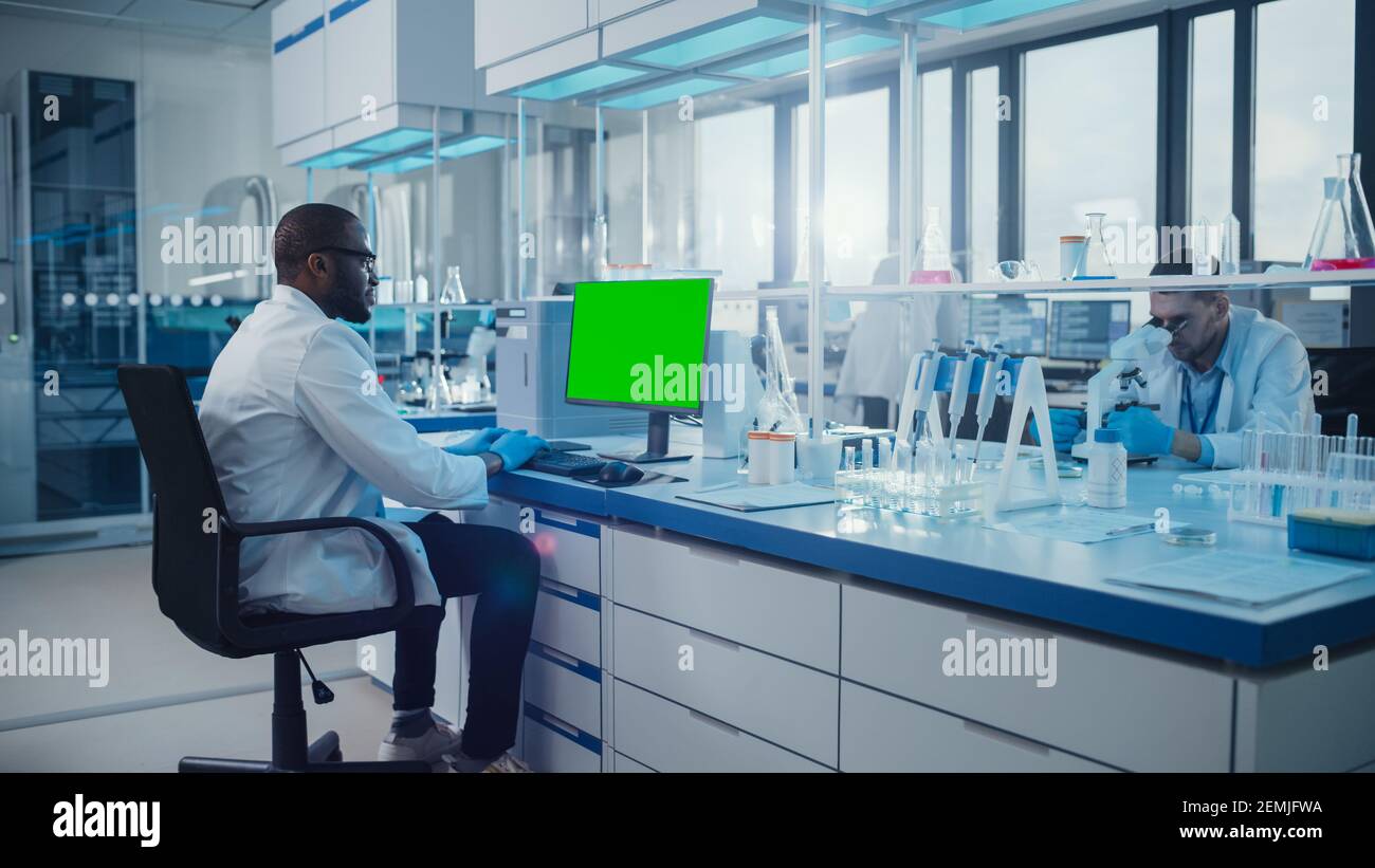 Modern Medical Research Laboratory: Scienziato che lavora sul computer mostrando Green Chroma Key Screen. Laboratorio scientifico, struttura di sviluppo della medicina con Foto Stock