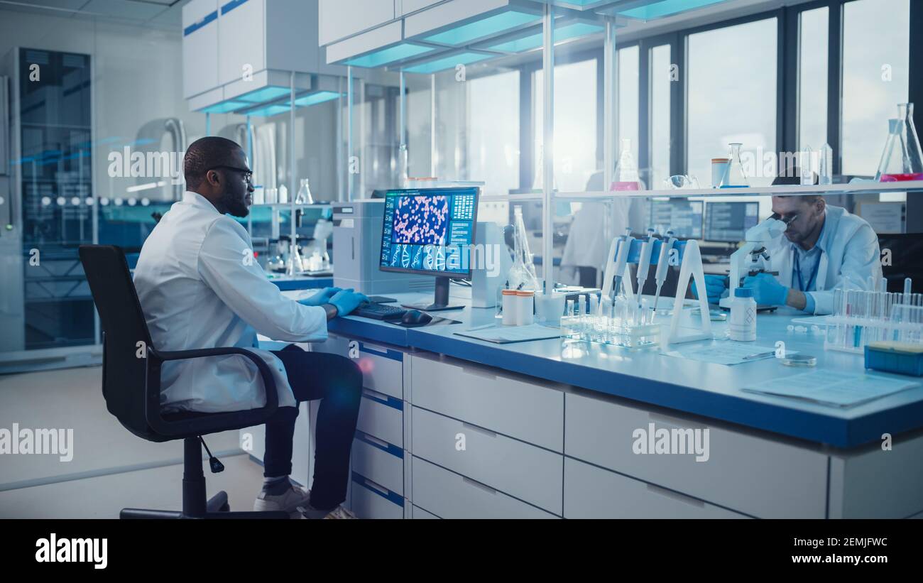 Laboratorio medico moderno: Scienziato maschile, digitando sulla tastiera lavorando sul computer, scren mostra il concetto di ricerca del DNA. Advanced Scientific Lab, Medicina Foto Stock