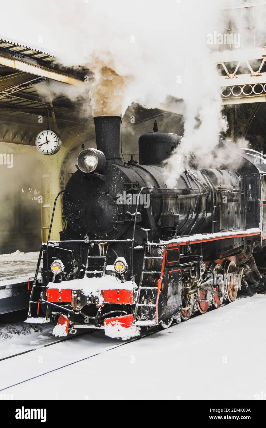 Treno a vapore d'epoca con partenza dalla stazione, in inverno. In attesa che i passeggeri salgano al binario Foto Stock