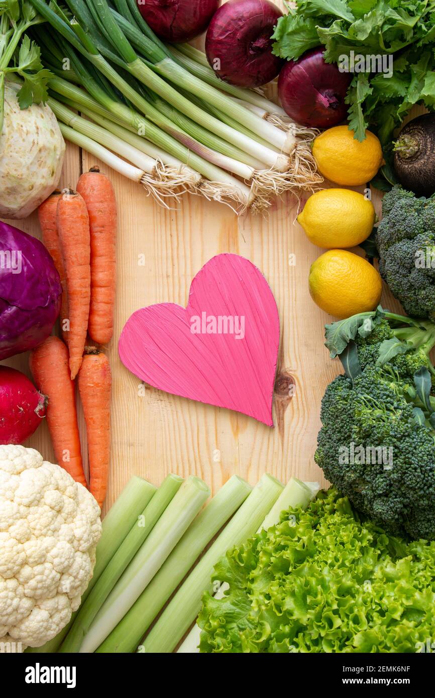 Per prendersi cura della vostra dieta, consumando troppe verdure per proteggere il vostro cuore. Cuore e verdure varie sulla tavola. Foto Stock