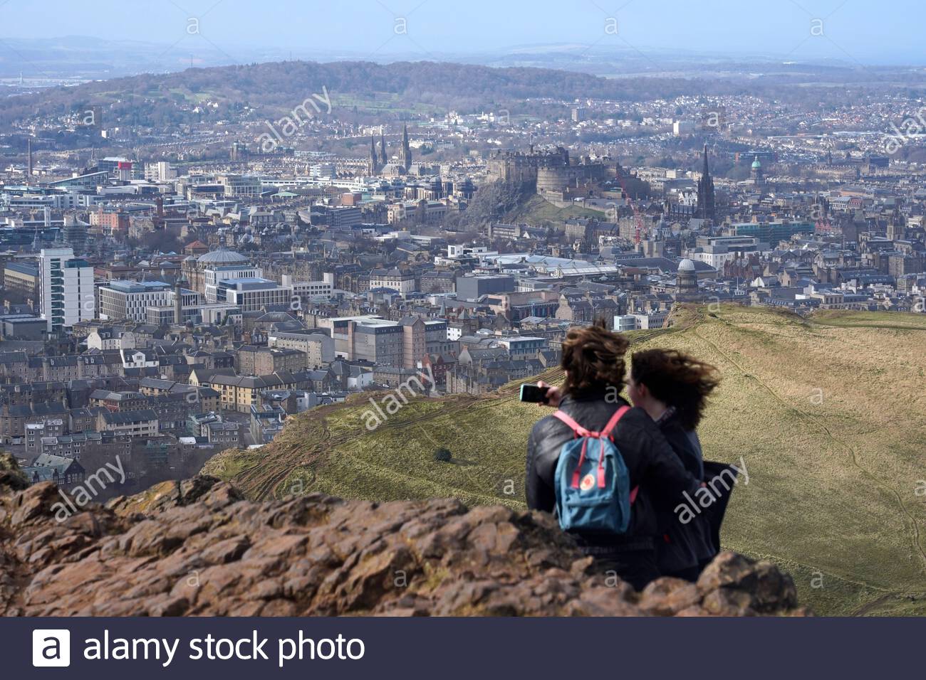 Edimburgo, Scozia, Regno Unito. 25 Febbraio 2021. Le persone che si godono il sole e all'aperto in Holyrood Park. Dalla cima di Arthurs si siede con una vista del Castello di Edimburgo. Credit: Craig Brown/Alamy Live News Foto Stock