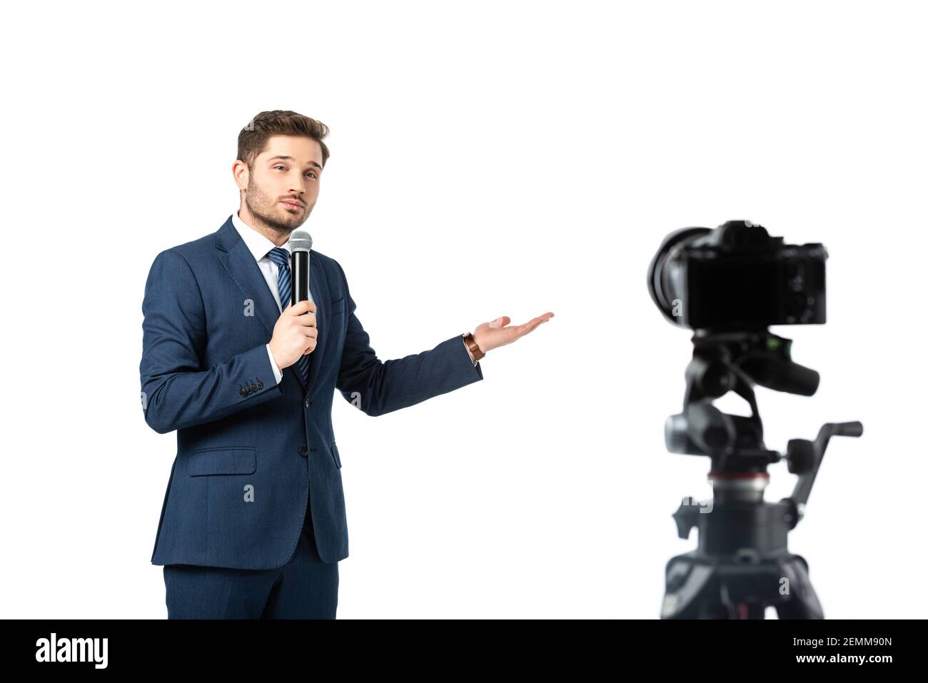 giornalista con microfono che punta con la mano mentre si guarda la fotocamera digitale isolato su bianco, primo piano sfocato Foto Stock