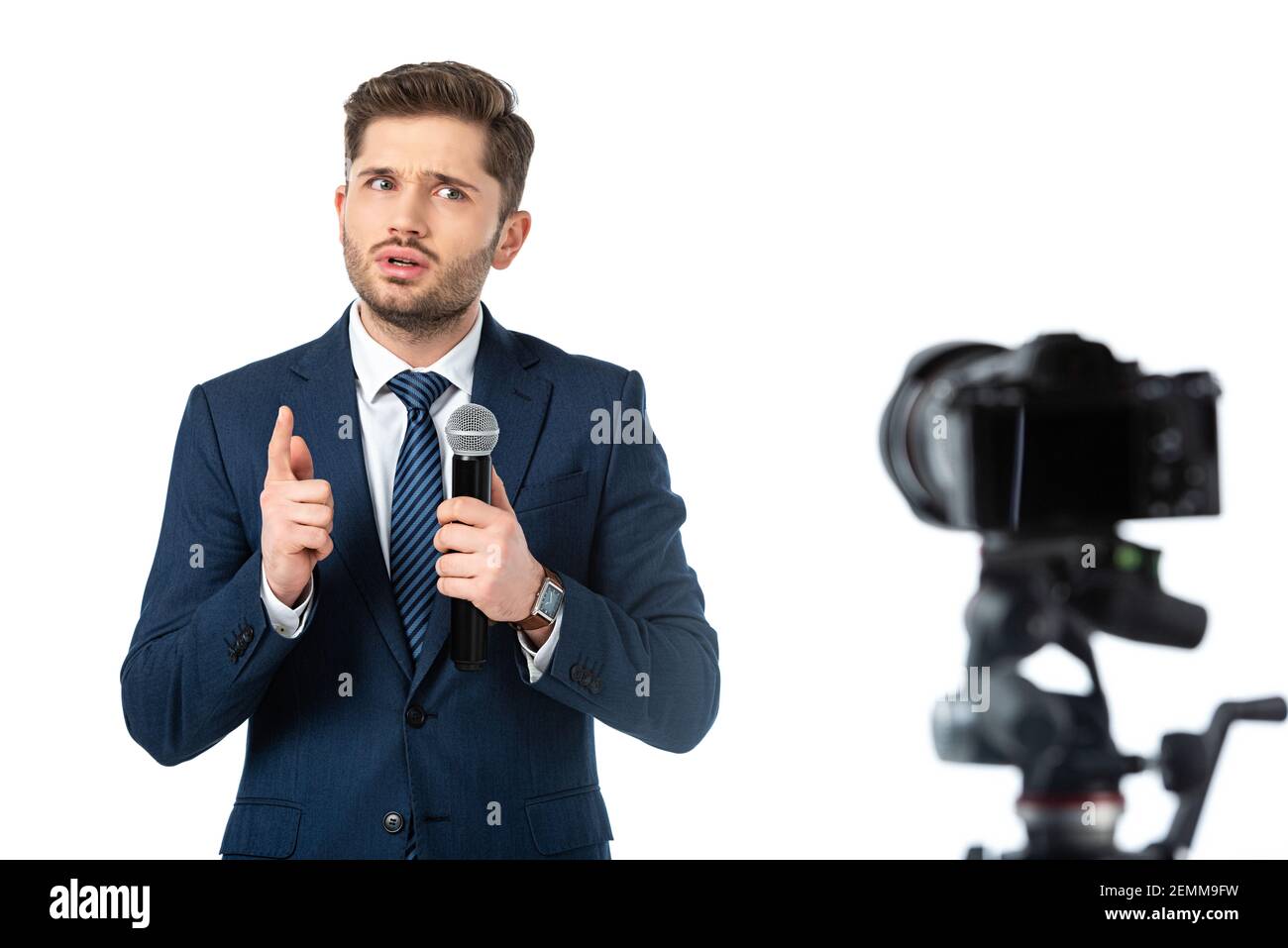 presentatore di notizie gravi con microfono rivolto con il dito vicino al digitale telecamera su primo piano sfocato isolata in bianco Foto Stock