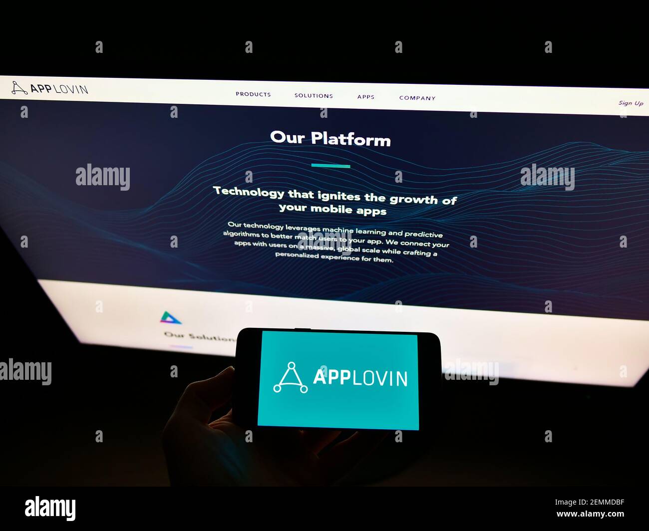 Persona che detiene un telefono cellulare con il logo aziendale della società di tecnologia mobile statunitense AppLovin Corp. Sullo schermo davanti alla pagina Web. Mettere a fuoco il display del telefono. Foto Stock
