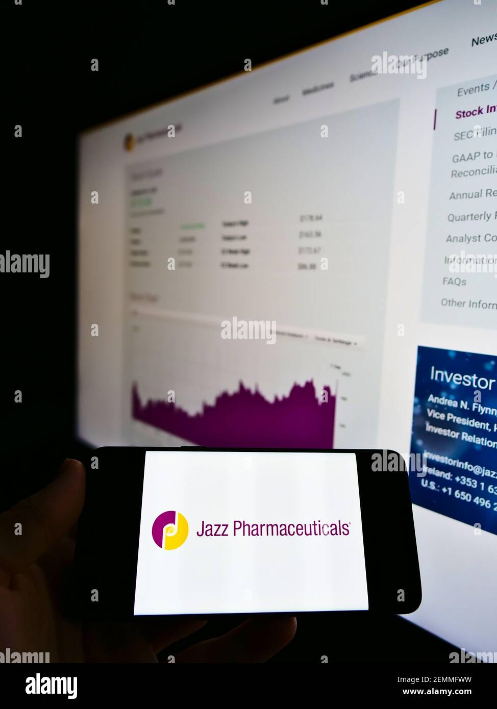 Persona che detiene smartphone con logo della società irlandese Jazz Pharmaceuticals plc sullo schermo di fronte al sito web con grafico. Focus sul display del cellulare. Foto Stock