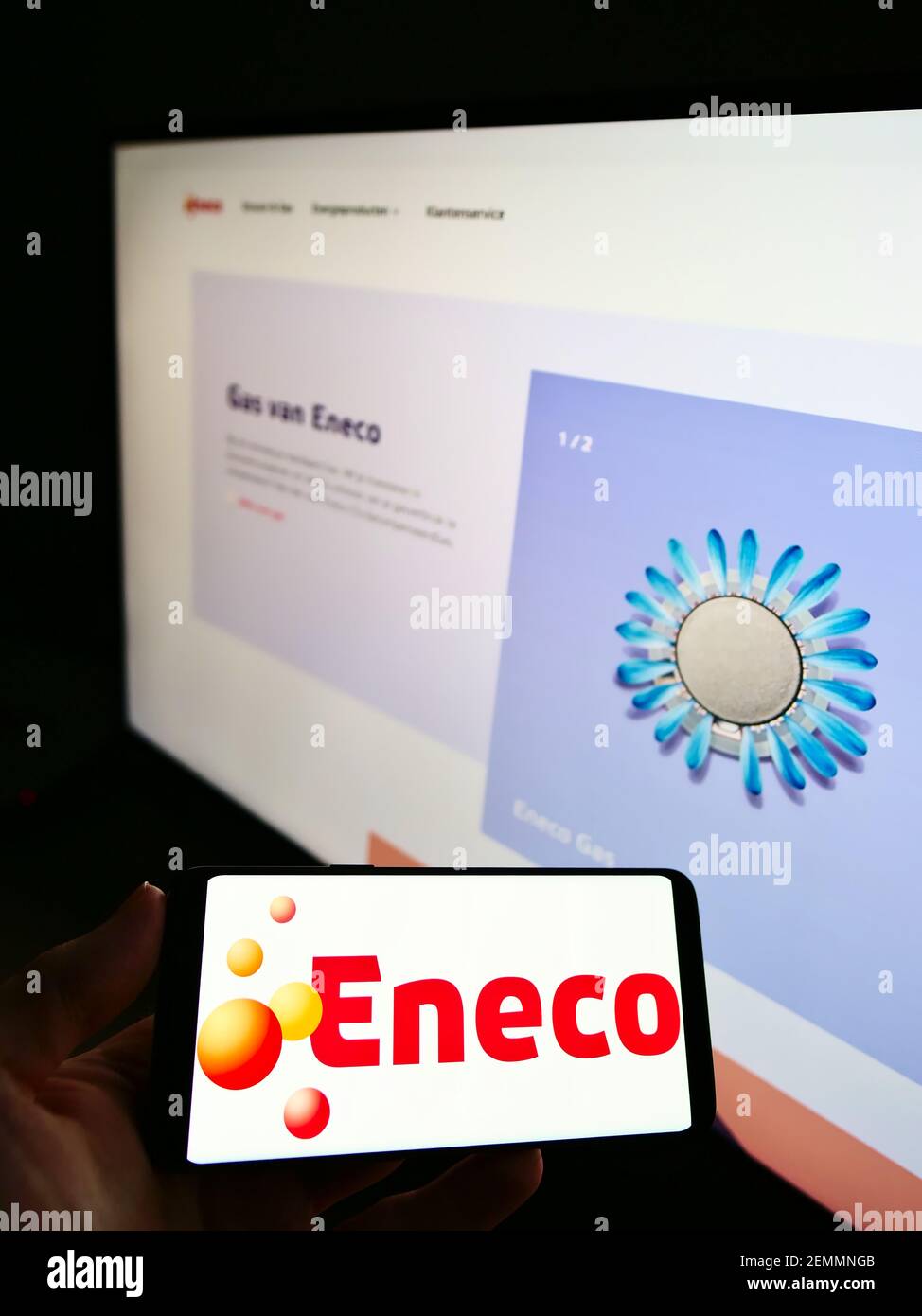 Persona che tiene il cellulare con il logo commerciale della società olandese di energia Eneco Groep NV sullo schermo di fronte al sito web. Focus sul display del telefono cellulare. Foto Stock