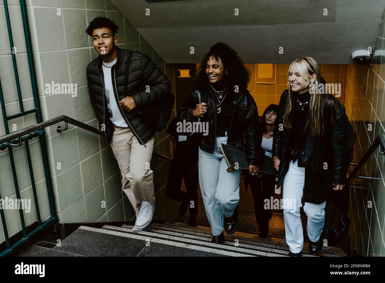 Amici sorridenti che salgono le scale alla metropolitana Foto Stock