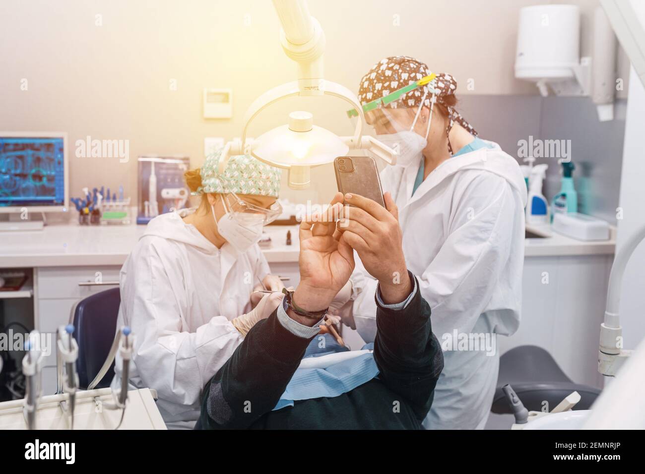 Paziente che prende un selfie nello studio dentistico. Tre persone. Medico femminile. Concetto di accoglienza e benessere. Sorrisi Foto Stock