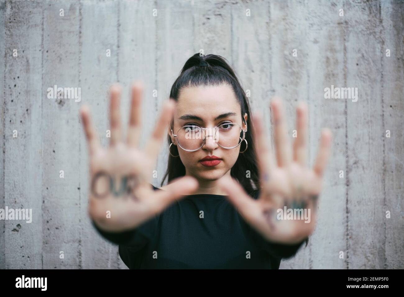 Il nostro pianeta testo scritto sulle palme di attivista femminile contro parete Foto Stock