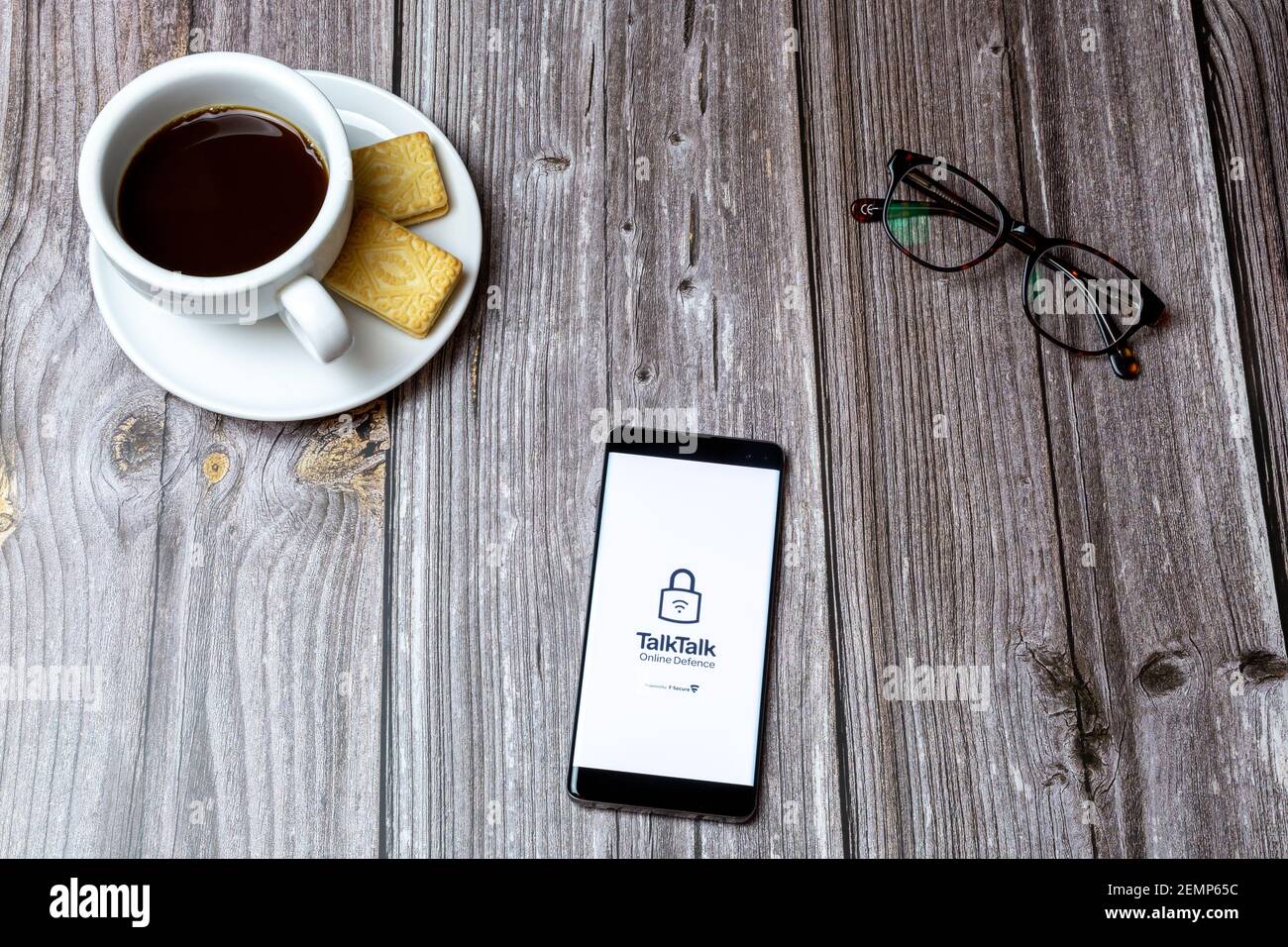Un telefono cellulare o cellulare su un tavolo di legno Con l'app Talk Talk Mobile aperta accanto a caffè e bicchieri Foto Stock