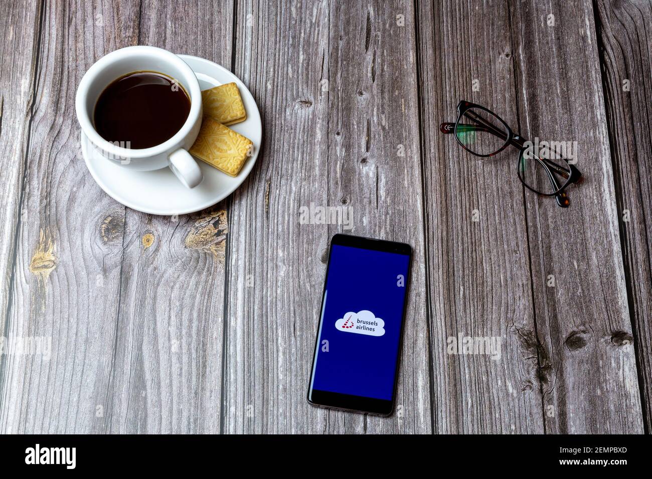 Un telefono cellulare o cellulare su un tavolo di legno Con l'app delle compagnie aeree di Bruxelles aperta accanto a un caffè e bicchieri Foto Stock