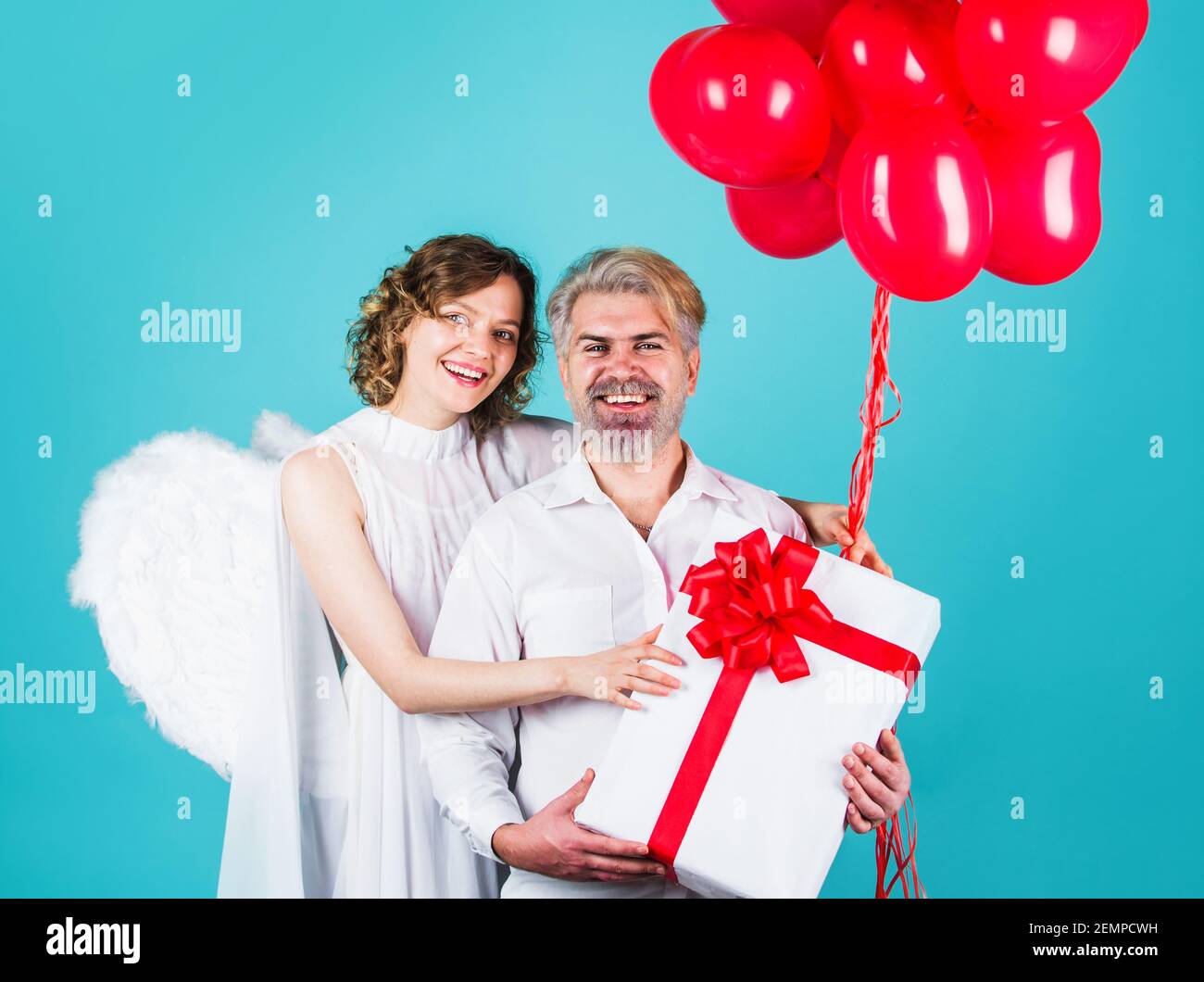 Coppia in giorno di San Valentino con palloncini cuore e dono. Angeli di famiglia. Regali di San Valentino. Foto Stock