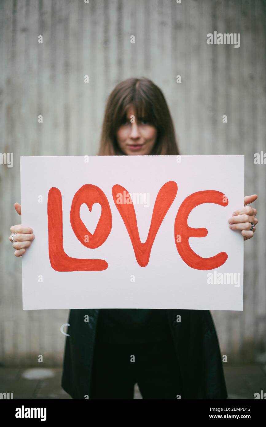 Attivista femminile con manifesto d'amore contro il muro Foto Stock