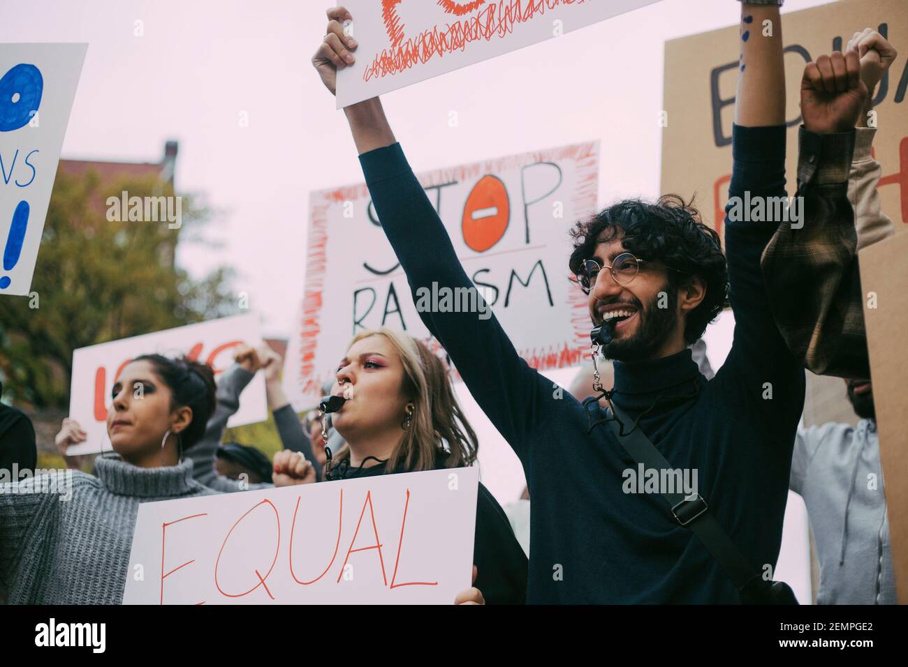 Uomo sorridente con attiviste femminili che protestano nel movimento sociale Foto Stock