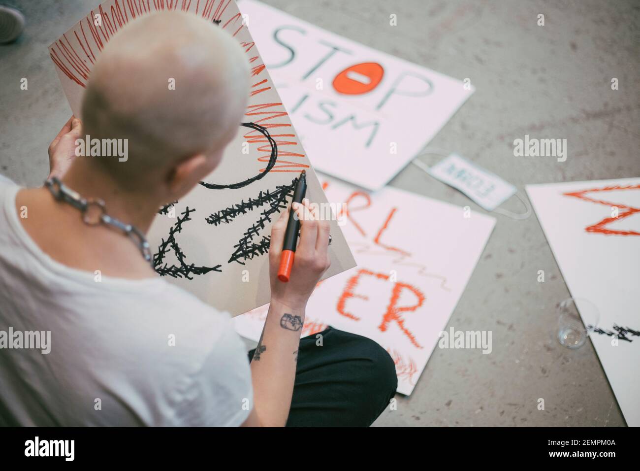Vista posteriore dell'attivista femminile calva che prepara un cartello per il sociale movimento Foto Stock